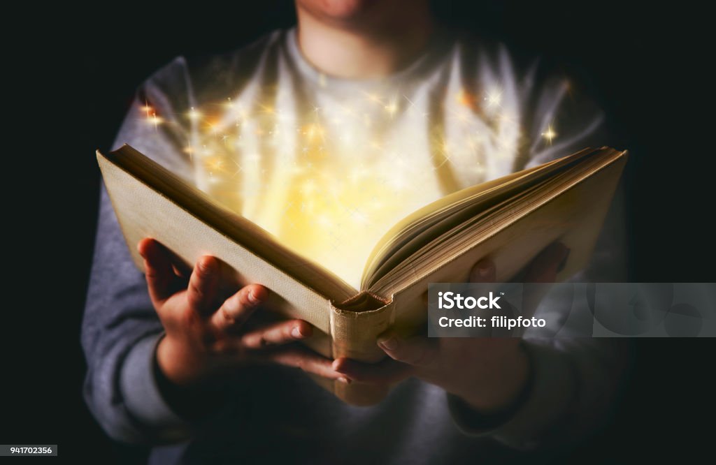 Light coming from book in woman's hands in gesture of giving Picture Book Stock Photo