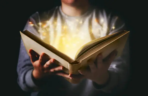 Light coming from book in woman's hands in gesture of giving