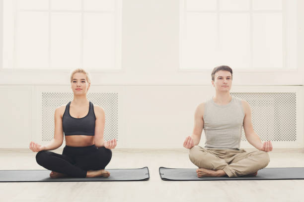 istock Young couple practicing yoga sitting in lotus pose 941702408