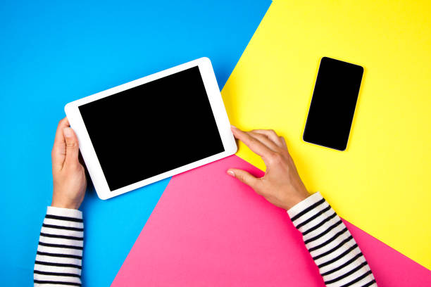 istock Woman's hands with tablet computer and smartphone on colorful background. 941705754