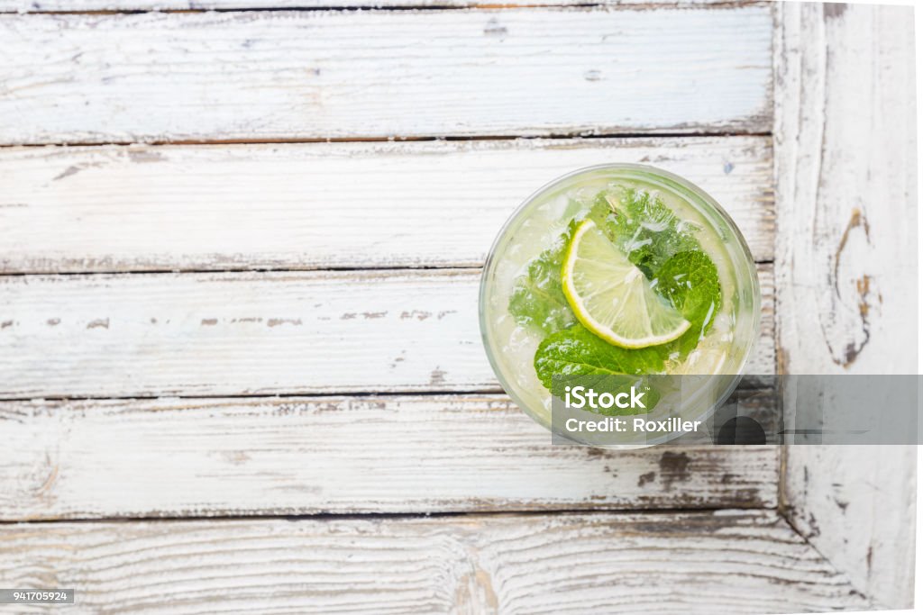 Mojito shot from birds eye view Refreshing mint cocktail mojito with rum and lime, cold drink or beverage with ice on white wooden background, top view Glass - Material Stock Photo