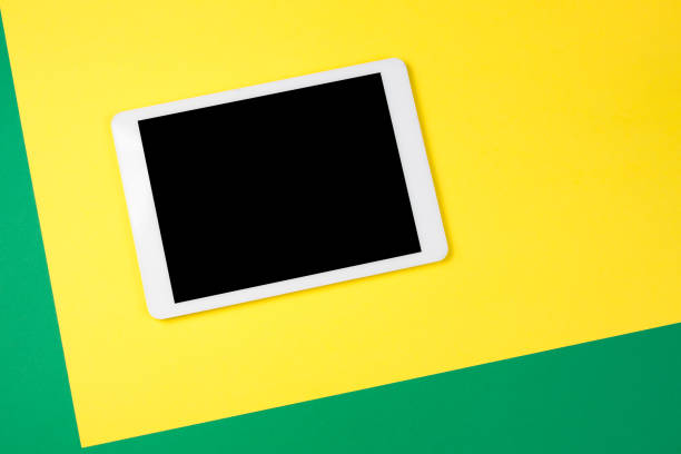 istock Digital tablet computer on yellow and green background. Top view. 941711552