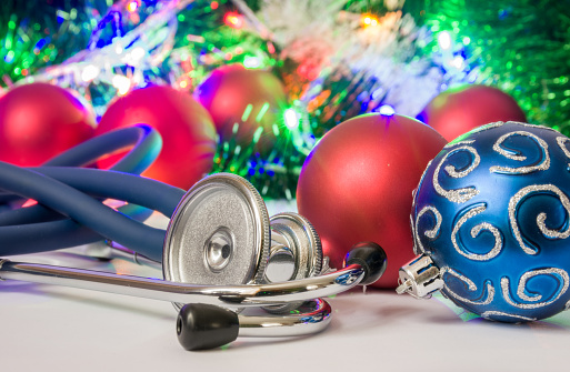 Medical Christmas and New Year photo - stethoscope or phonendoscope are located near balls for Christmas tree in blurry background with electric garlands lights and toys
