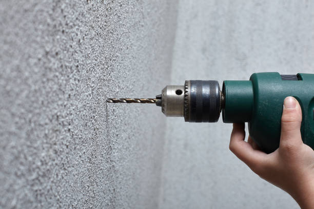 istock Worker drilling a hole into the wall with an electric drill. 941715956