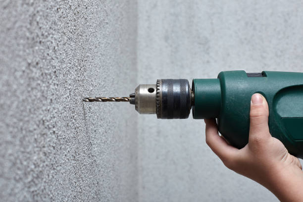 istock Worker drilling a hole into the wall with an electric drill. 941719256