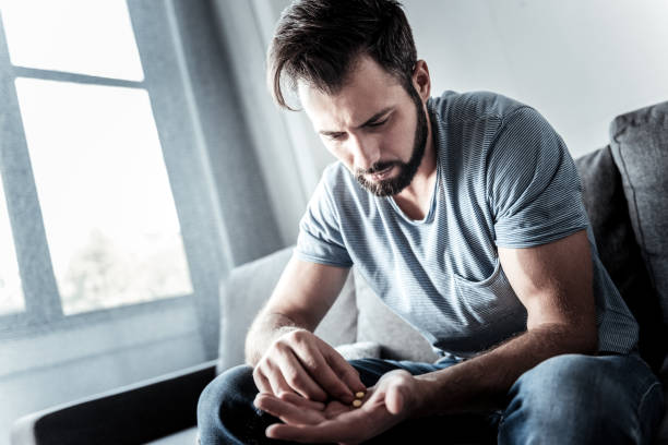 istock Sad moody man holding pills 941719918