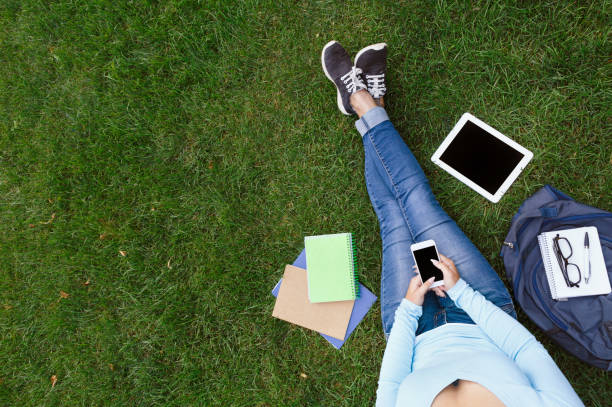 istock Woman chatting on mobile sitting on the green grass 941723814