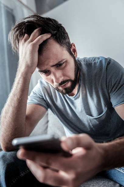 istock Sad depressed man holding his smartphone 941723888