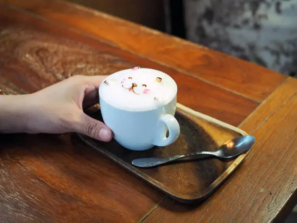 Photo of A mug of cute bear shape foam on tasty hot mocha on wooden tray.