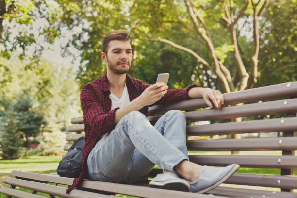 istock Handsome man sitting and using smartphone outdoors 941727972
