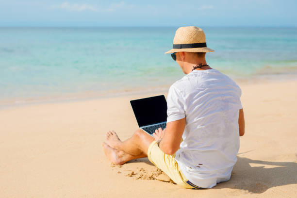 istock Relaxed man working with laptop on the beach 941728446