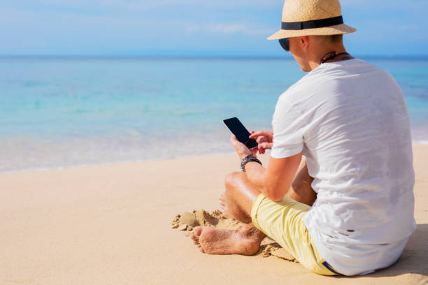 istock Man on the beach with mobile phone 941728510