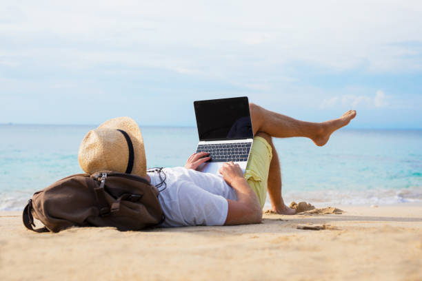 istock Relaxed man with laptop on the beach 941728632