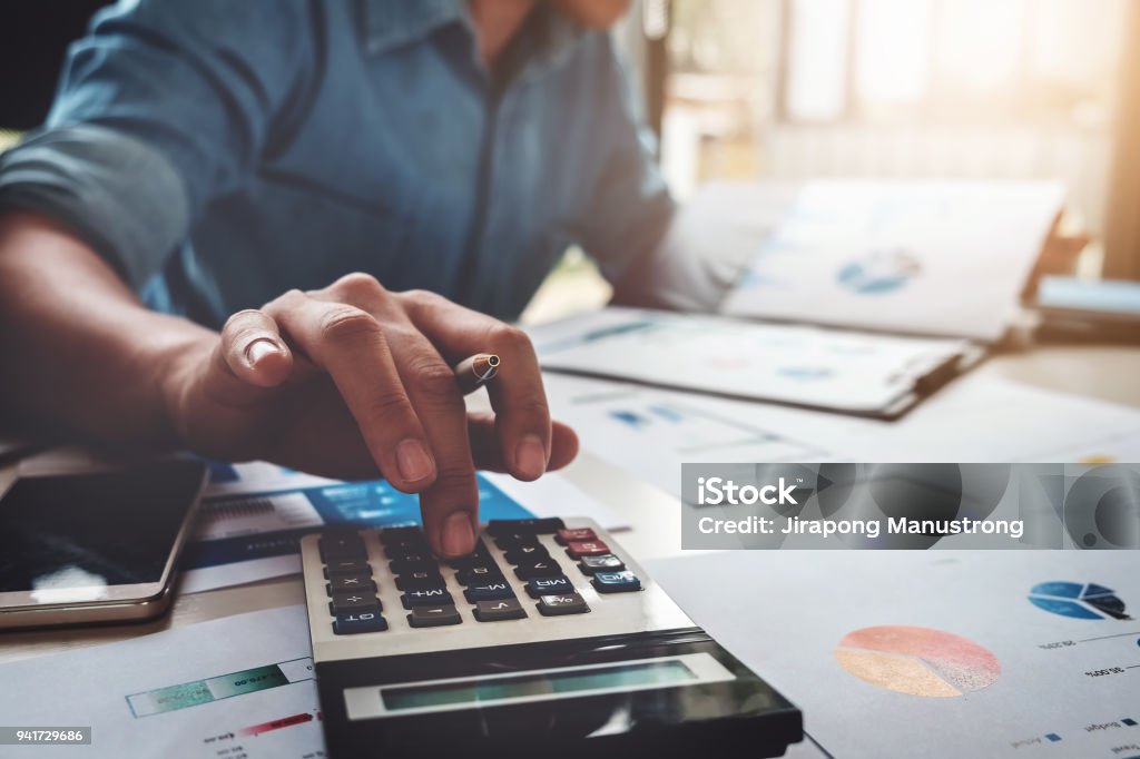 Business accounting concept, Business man using calculator with computer laptop, budget and loan paper in office. Finance Stock Photo