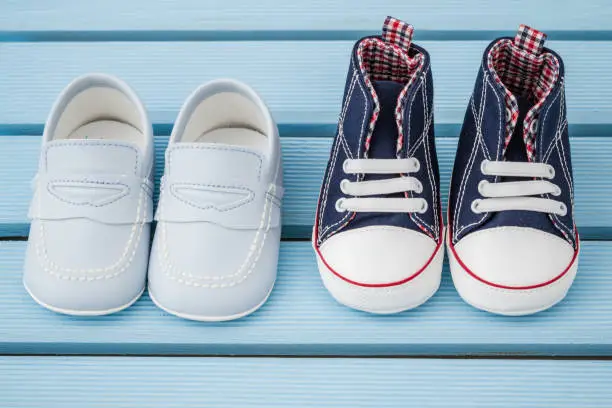 Pairs of dark blue,white baby sneakers and blue baby shoes over blue background