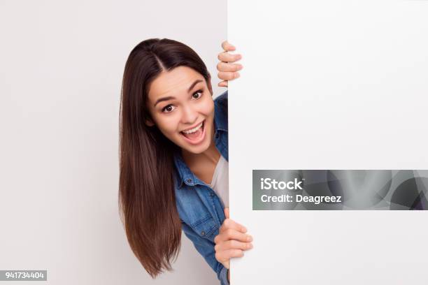 Happy Amazed Young Girl Is Popping Out From White Blank Banner Stock Photo - Download Image Now