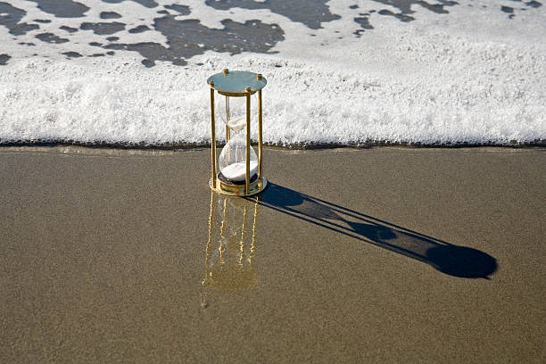 sablier une minuterie et montante surf du littoral de la plage tide - view into land photos et images de collection