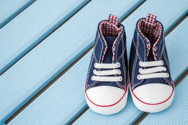 Pair of dark blue and white baby sneakers over blue background