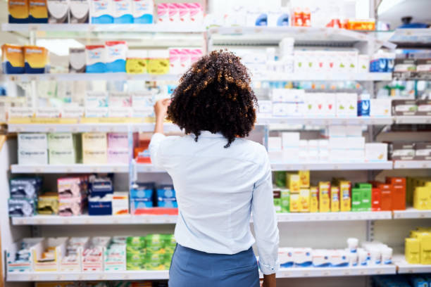 So many choices Rearview shot of a young woman looking at products in a pharmacy chemist stock pictures, royalty-free photos & images