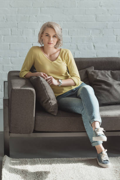 istock beautiful girl sitting on sofa and looking at camera 941742028