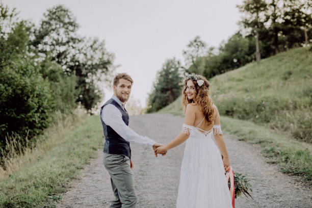 istock Beautiful bride and groom in green nature, holding hands. 941749340
