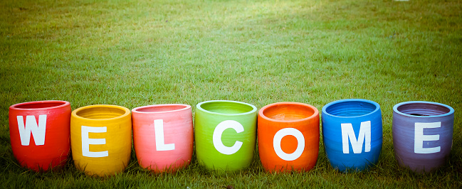 Welcoming and greetings concept with welcome word colorful on garden background.