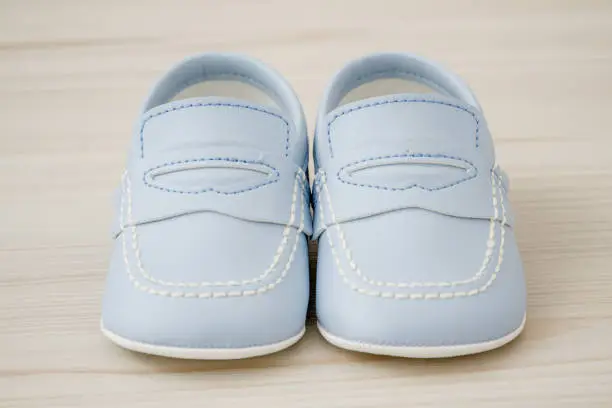 Pair of  classic blue baby shoes over white wooden background