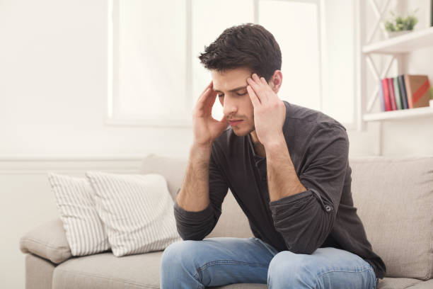 istock Young man having headache at home 941761790