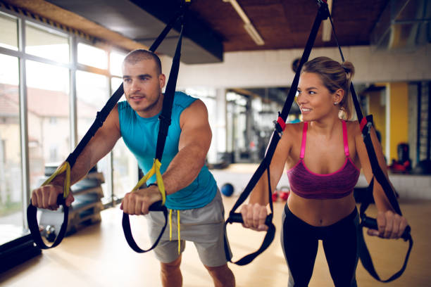 istock Couple doing arm exercises with suspension straps at gym 941766598