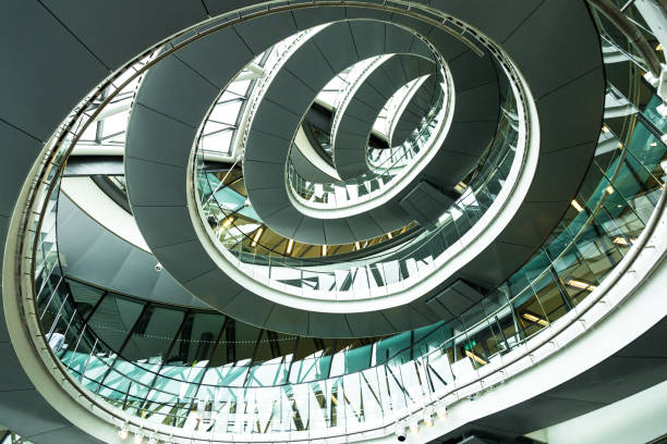 Abstract modern architecture and winding staircase in London, UK Wide angle color image depicting ultra modern contemporary interior architecture in City Hall (a public building in London that is open to the public) in London, UK. Looking up we can see a modern spiral staircase winding around the entire building, and also the windows that surround the building, letting in as much natural light as possible. Lots of room for copy space. gla building stock pictures, royalty-free photos & images