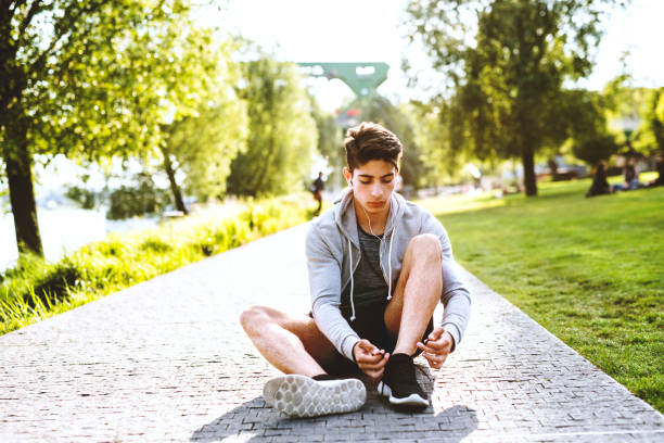 istock Runner in the city sitting on concrete path tying shoelaces. 941769814