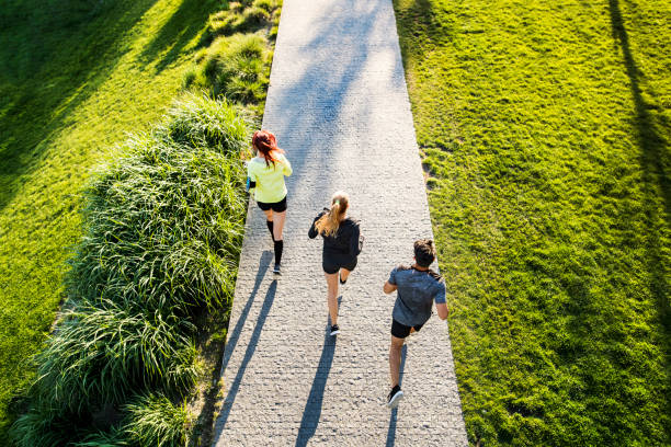 Young athtletes in the city running in park. Group of young athletes running on a concrete path in green sunny park. Top view. sports shoe photos stock pictures, royalty-free photos & images