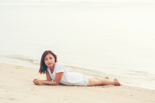 Asian young girl lying down on the beach alone