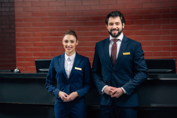 istock hotel receptionists standing together in front of counter and looking at camera 941772700