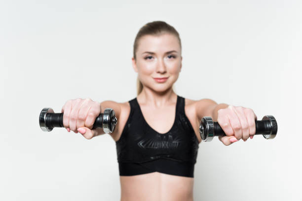 istock Dumbbells in sportive female hands isolated on white 941772748