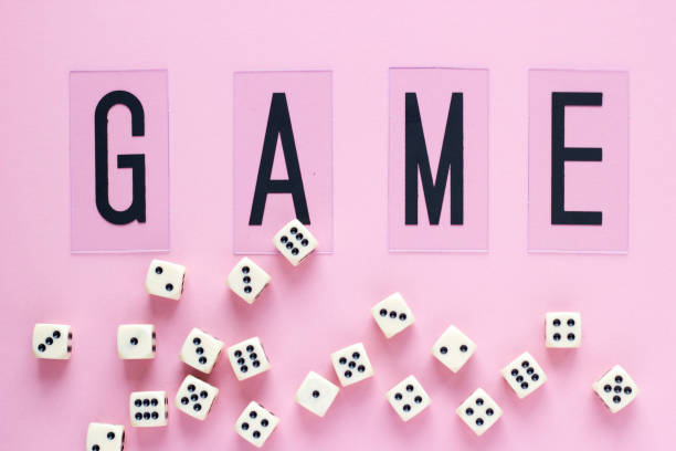 Gaming dice with word GAME on pink background.