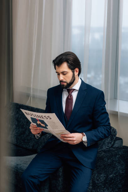 istock serious businessman reading newspaper at hotel room 941776078