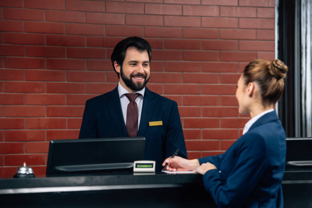istock hotel receptionist talking to customer while she signing contract at counter 941778828