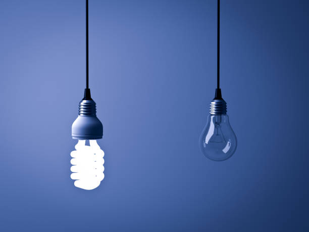 istock Eco energy saving light bulb , one glowing compact fluorescent lightbulb and unlit incandescent bulb on dark blue background 941778846