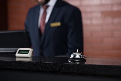 hotel reception desk with bell and blurred receptionist on background