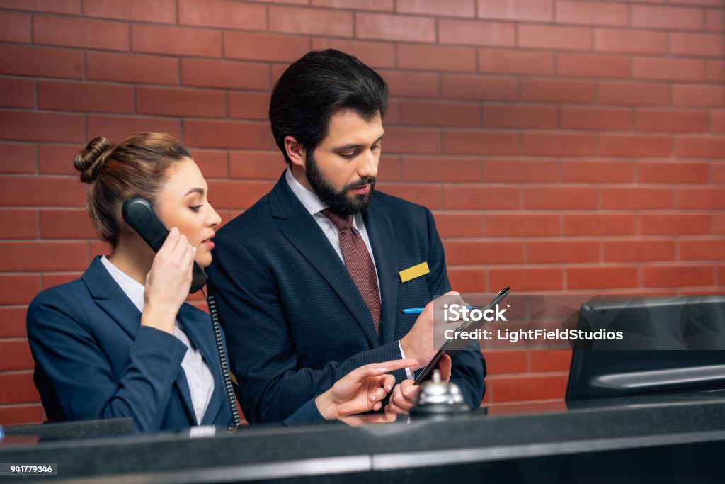 concentrated hotel receptionists receiving call from customer at workplace Hotel Stock Photo