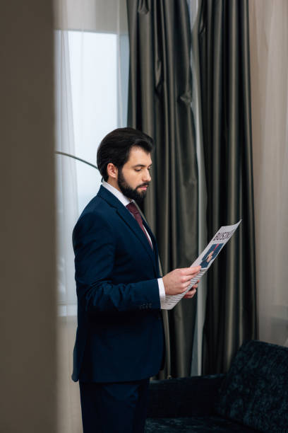 istock handsome businessman reading newspaper at hotel room 941781722