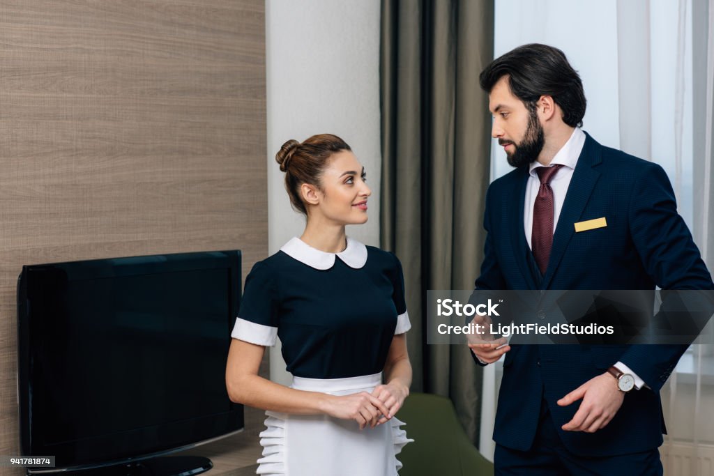 giovane personale di servizio alberghiero parlando in suite - Foto stock royalty-free di Albergo