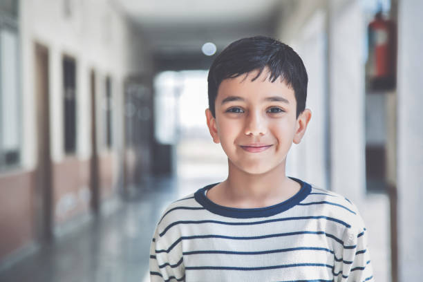 Portrait of a young school boy smiling Close-up portrait of smiling 8-9 years Indian kid, standing straight at school campus in school uniform and looking at camera one boy only photos stock pictures, royalty-free photos & images