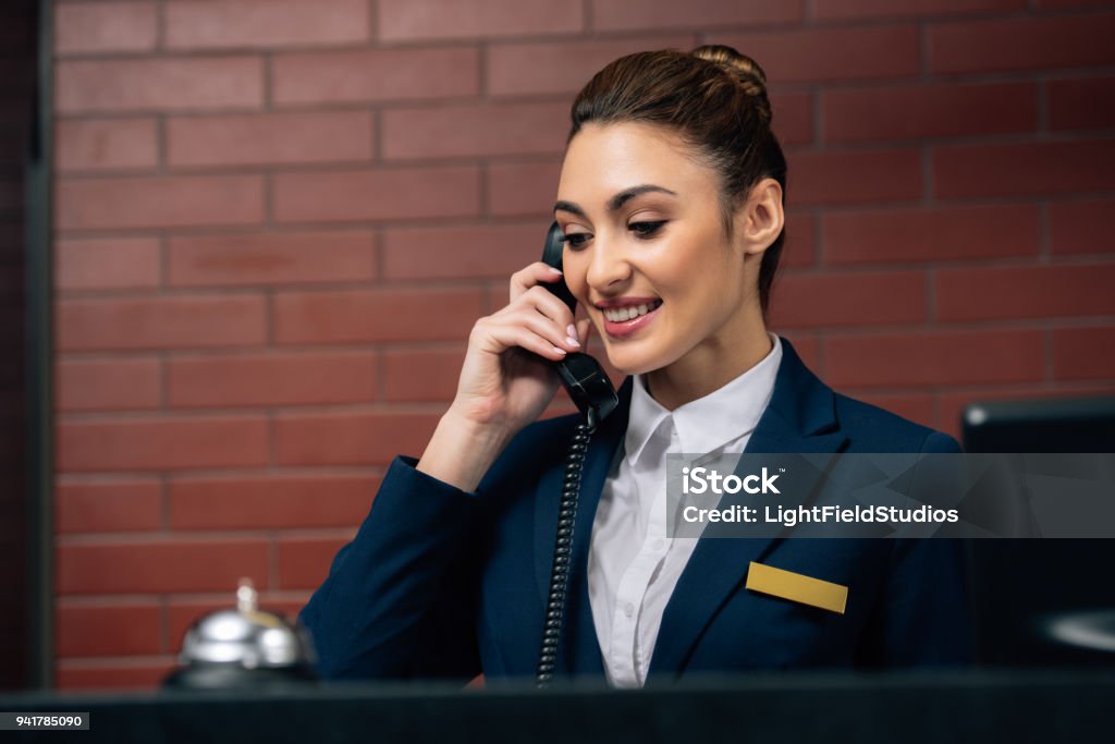 giovane bella receptionist hotel ricevere chiamata sul posto di lavoro - Foto stock royalty-free di Albergo