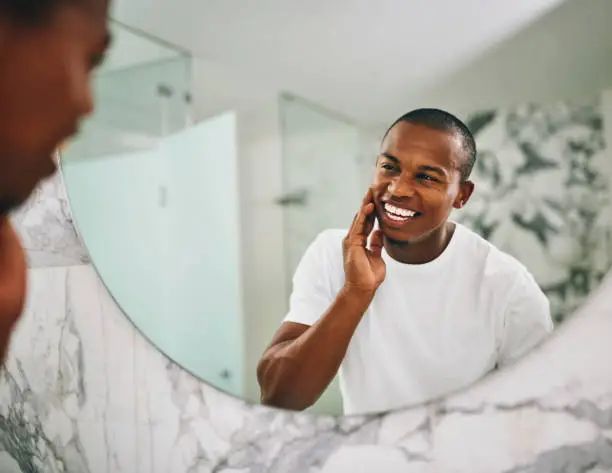 Shot of a young man going through his morning routine in the bathroom at home