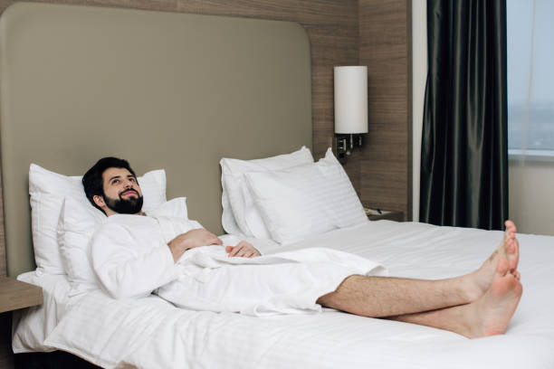 istock handsome man in bathrobe relaxing on bed at hotel suite 941785484