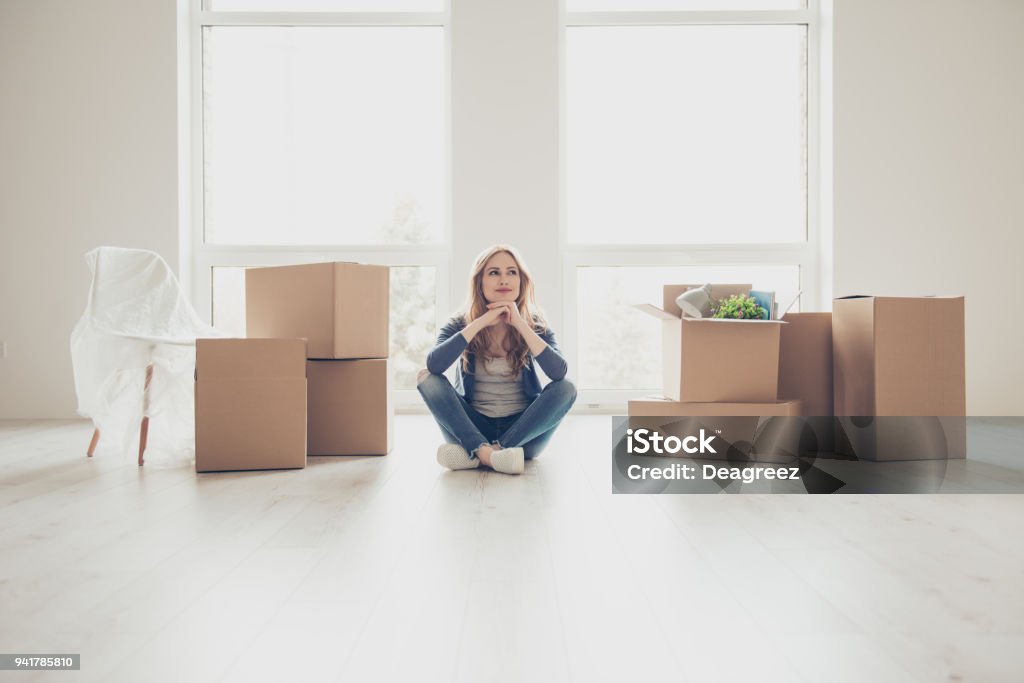 ¡Sueño hecho realidad! Retrato de joven mujer bonita sentada en el suelo y pensando cómo desempaquetar todas las cosas - Foto de stock de Piso - Residencia libre de derechos