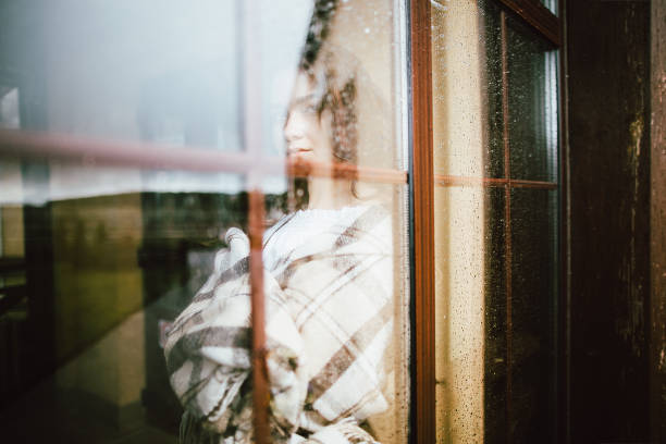 istock Young woman looking through window 941788418