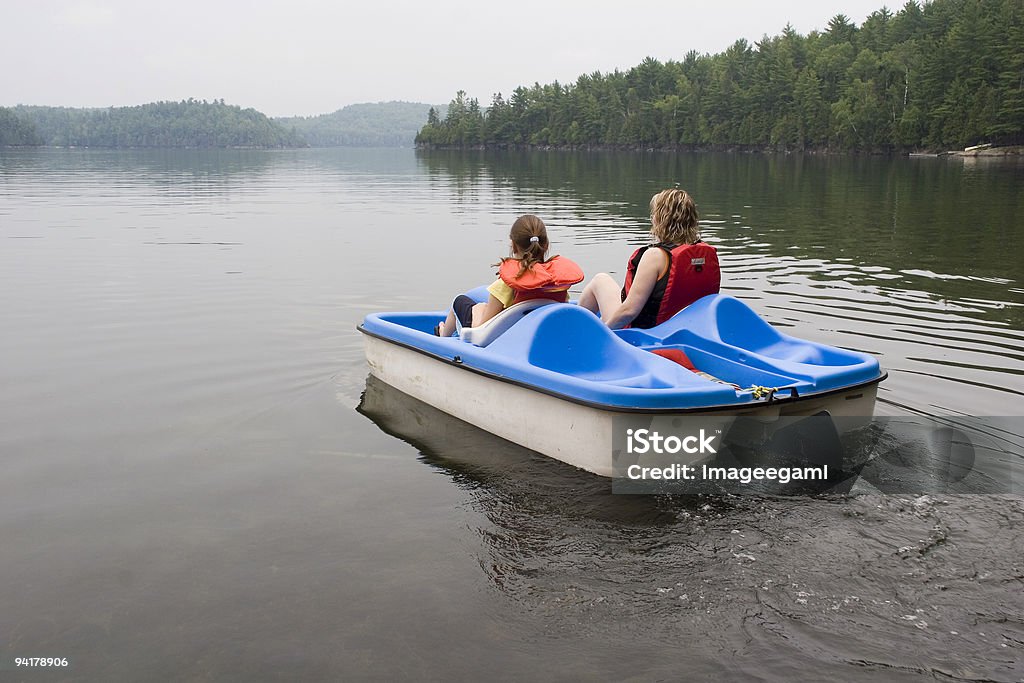 A mother and daughter riding a pedelo wearing life jackets Please visit my AT THE BEACH - LAKE LIGHTBOX (Just click on the thumbnail): Pedal Boat Stock Photo